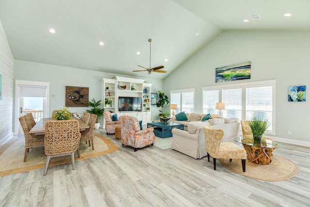 living room featuring ceiling fan, high vaulted ceiling, and light wood-type flooring