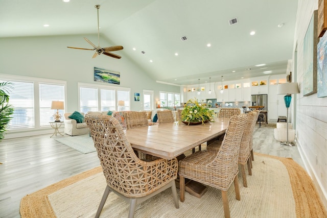 dining area featuring high vaulted ceiling and light hardwood / wood-style floors