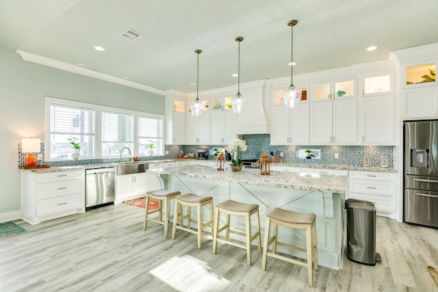 kitchen featuring white cabinetry, light stone countertops, stainless steel appliances, and a center island