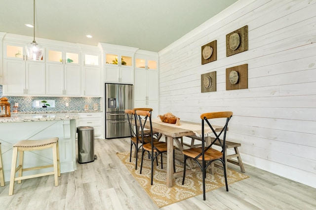 dining area featuring wood walls and light wood-type flooring