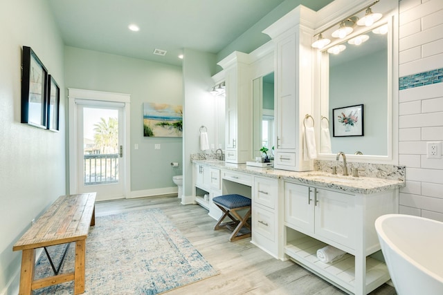 bathroom featuring vanity, a bathtub, wood-type flooring, and toilet