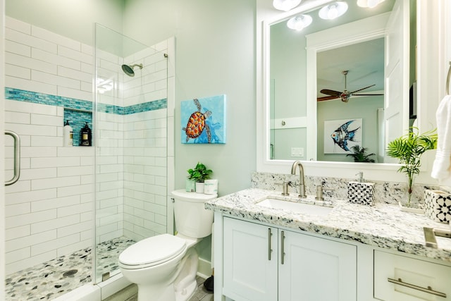 bathroom featuring vanity, ceiling fan, a shower with shower door, and toilet