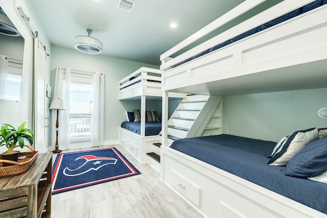 bedroom featuring a barn door and light hardwood / wood-style flooring