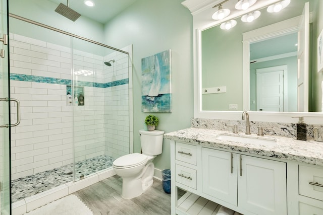 bathroom featuring vanity, hardwood / wood-style flooring, a shower with door, and toilet