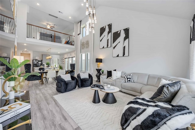 living room with a high ceiling, a chandelier, and light hardwood / wood-style flooring