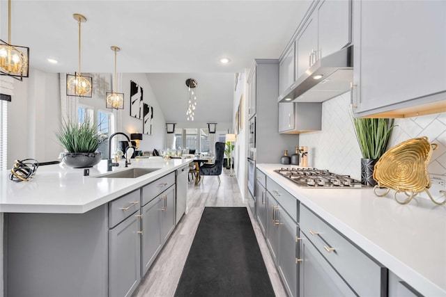 kitchen featuring sink, tasteful backsplash, gray cabinets, pendant lighting, and stainless steel appliances