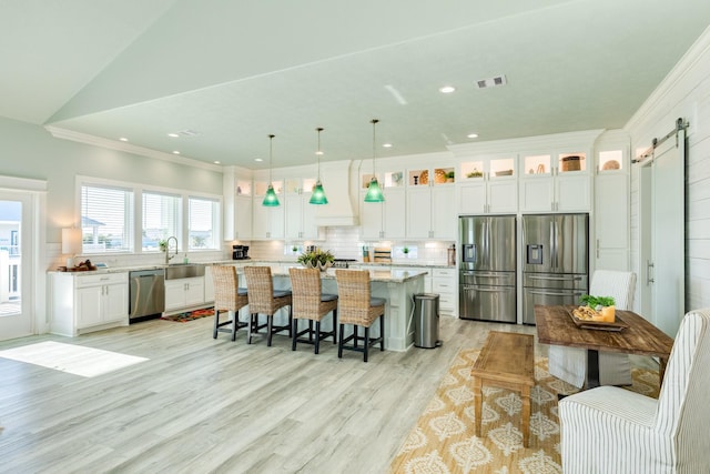 kitchen with pendant lighting, sink, appliances with stainless steel finishes, a kitchen island, and a barn door