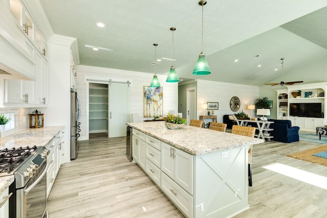 kitchen featuring white cabinetry, a barn door, a large island, and pendant lighting