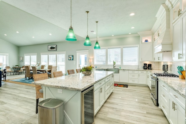 kitchen with premium range hood, wine cooler, a breakfast bar, stainless steel gas stove, and a center island