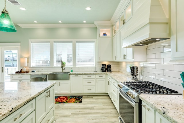 kitchen with sink, premium range hood, appliances with stainless steel finishes, white cabinets, and decorative light fixtures