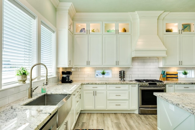 kitchen featuring sink, tasteful backsplash, light stone counters, white cabinets, and gas range