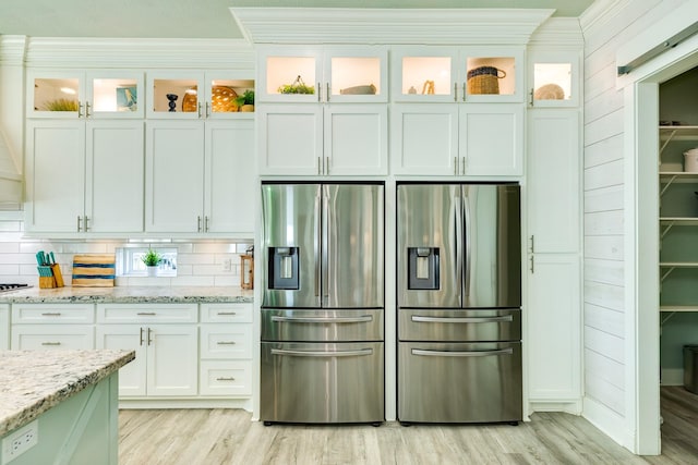 kitchen with white cabinetry, light hardwood / wood-style floors, light stone countertops, and stainless steel fridge with ice dispenser