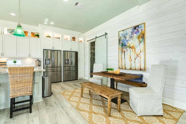 kitchen featuring a barn door, white cabinetry, stainless steel fridge, and decorative light fixtures