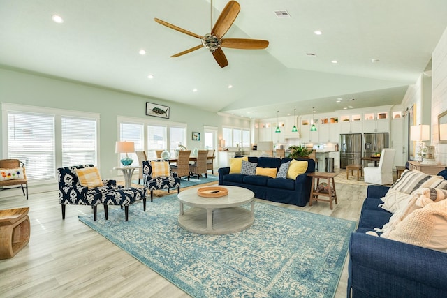 living room featuring vaulted ceiling, ceiling fan, and light hardwood / wood-style floors