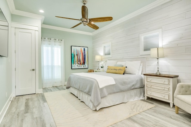 bedroom featuring ceiling fan, ornamental molding, wooden walls, and light hardwood / wood-style flooring