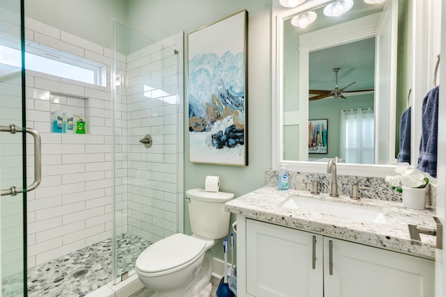 bathroom featuring vanity, a shower with shower door, ceiling fan, and toilet