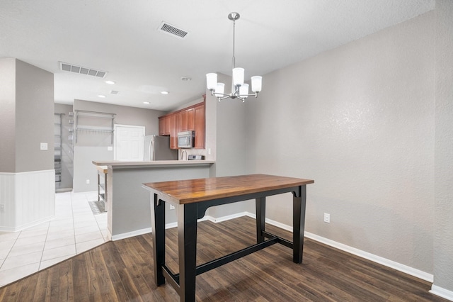 kitchen with an inviting chandelier, wood-type flooring, stainless steel appliances, and kitchen peninsula