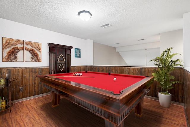 game room featuring hardwood / wood-style flooring, billiards, wooden walls, and a textured ceiling