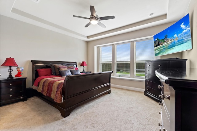 bedroom with light carpet, a raised ceiling, and ceiling fan