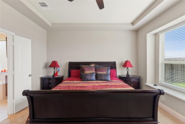 bedroom with light colored carpet, a raised ceiling, and ceiling fan