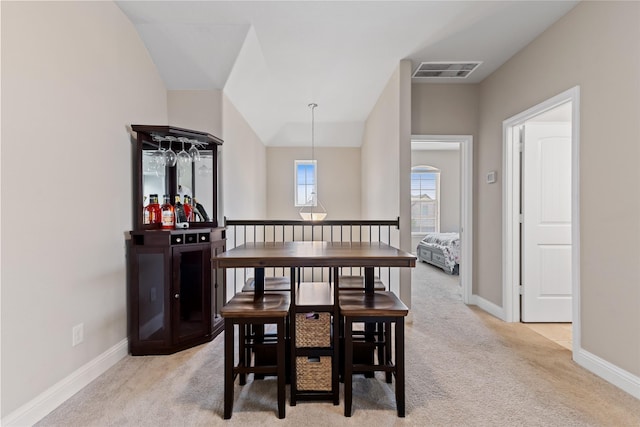 carpeted dining space with vaulted ceiling