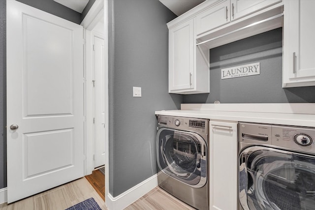 laundry area with cabinets, washer and clothes dryer, and light hardwood / wood-style flooring