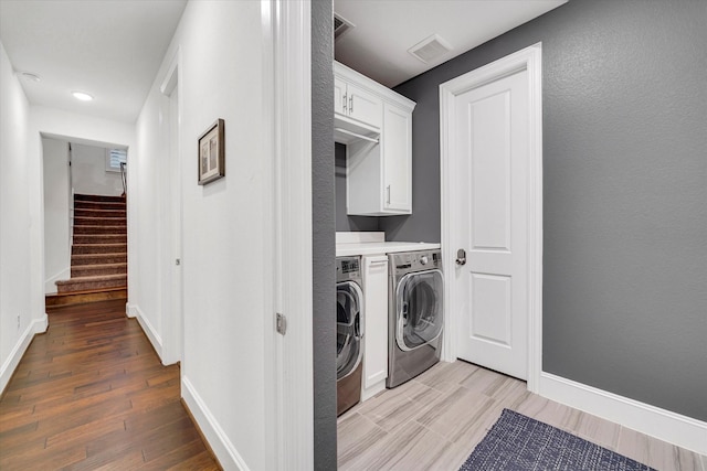 laundry room with separate washer and dryer, light hardwood / wood-style flooring, and cabinets