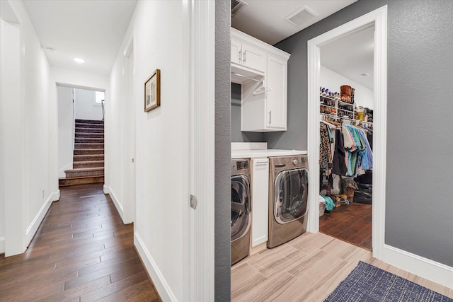 washroom featuring light hardwood / wood-style flooring, washing machine and dryer, and cabinets