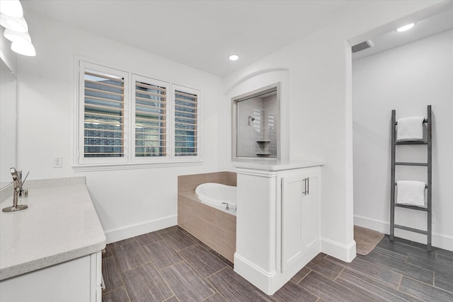 bathroom with vanity and tiled bath