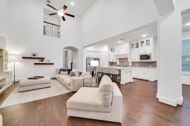 living room featuring dark hardwood / wood-style flooring, high vaulted ceiling, and ceiling fan