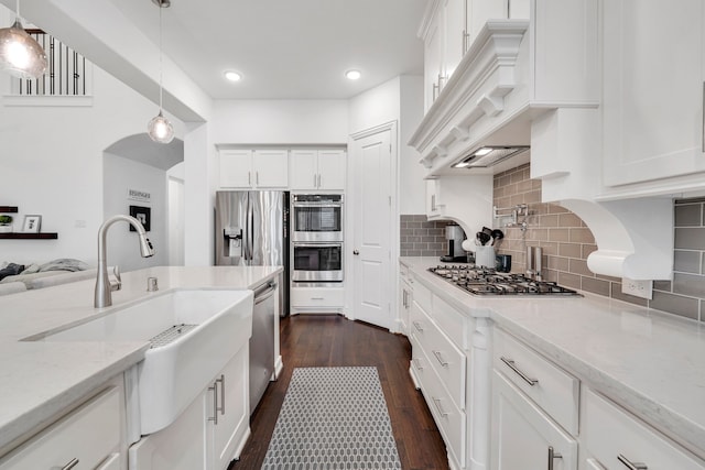 kitchen featuring hanging light fixtures, white cabinetry, light stone countertops, and stainless steel appliances