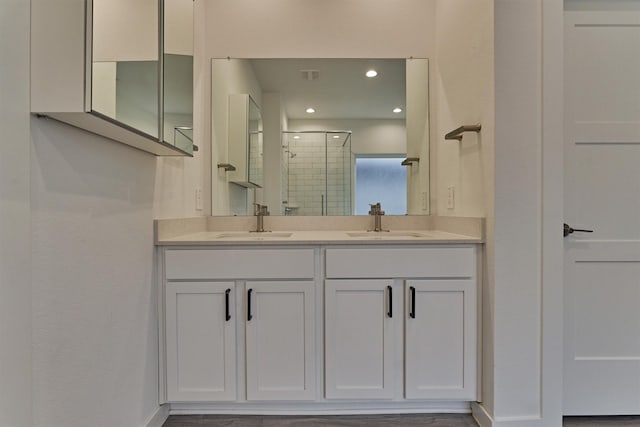 bathroom featuring a shower with door and vanity