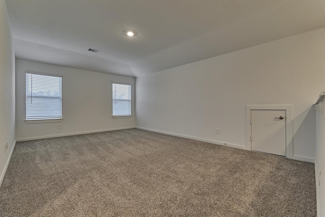 carpeted spare room with vaulted ceiling