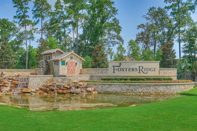 community / neighborhood sign featuring a yard and a water view