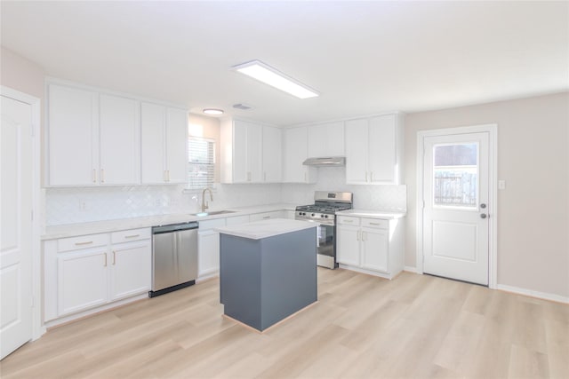 kitchen with sink, appliances with stainless steel finishes, a center island, light hardwood / wood-style floors, and white cabinets