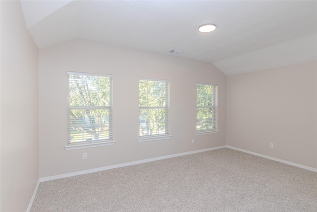 unfurnished room with vaulted ceiling, light carpet, and a wealth of natural light