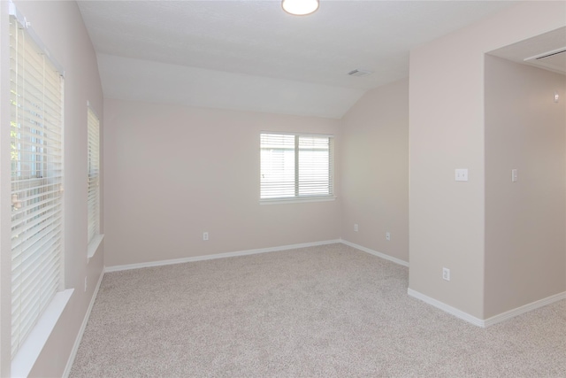 carpeted spare room with vaulted ceiling