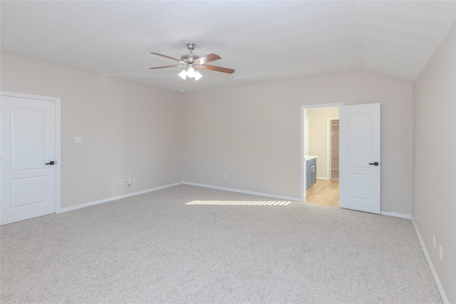 empty room featuring vaulted ceiling, light colored carpet, and ceiling fan