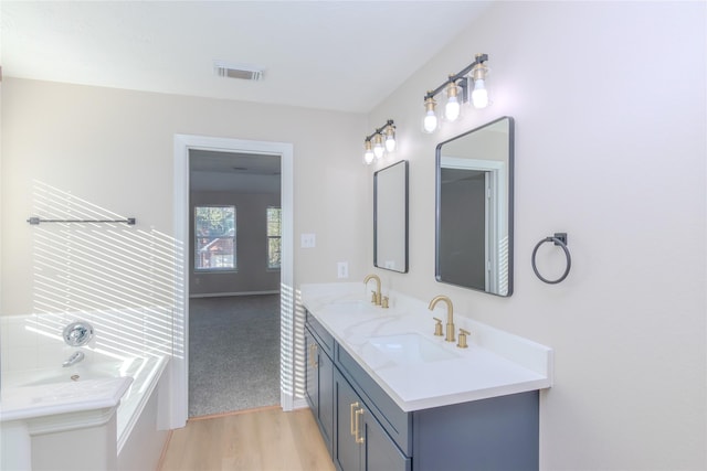 bathroom with hardwood / wood-style flooring, vanity, and a bathtub