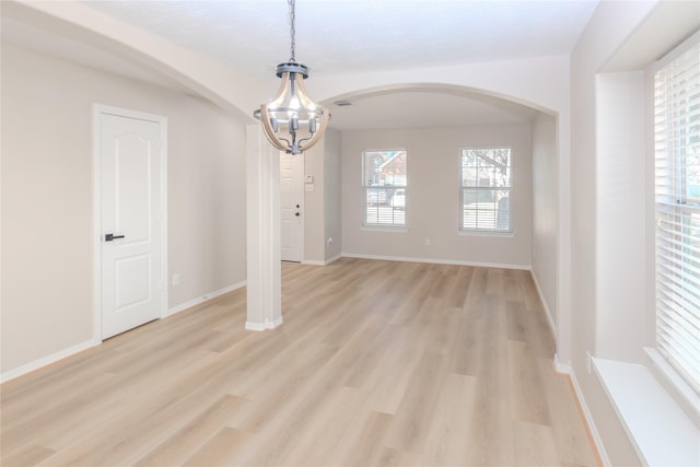 empty room featuring an inviting chandelier and light hardwood / wood-style flooring