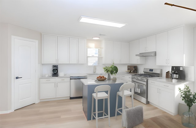 kitchen with sink, stainless steel appliances, a center island, and white cabinets