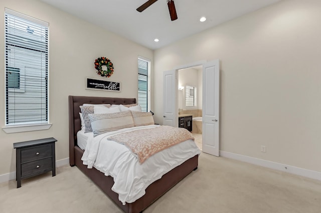 bedroom with ceiling fan, ensuite bathroom, and light colored carpet