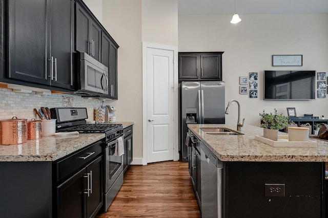 kitchen featuring sink, decorative light fixtures, appliances with stainless steel finishes, an island with sink, and decorative backsplash