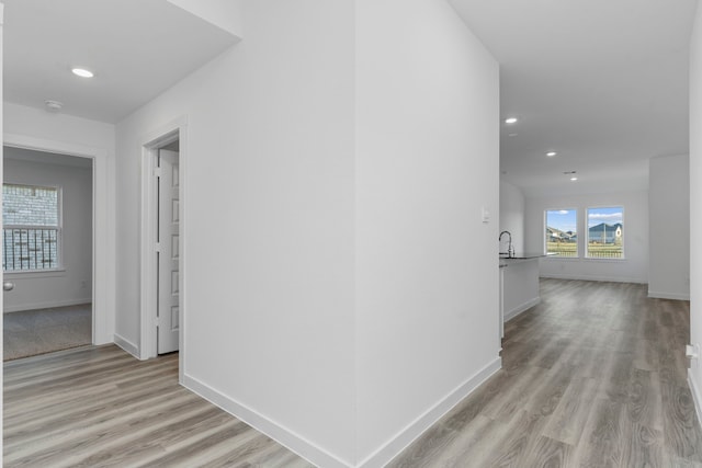 hallway with sink and light hardwood / wood-style floors