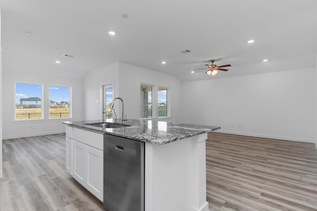 kitchen featuring sink, a center island with sink, dishwasher, dark stone counters, and white cabinets