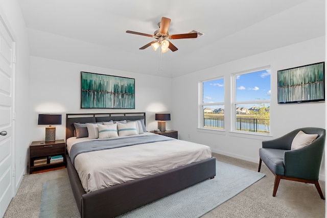 carpeted bedroom with a water view and ceiling fan