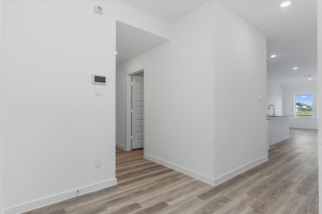 hall with sink and light wood-type flooring