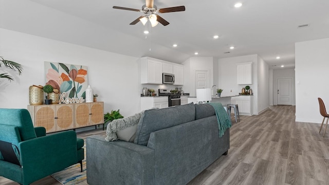 living room featuring sink, ceiling fan, and light hardwood / wood-style flooring