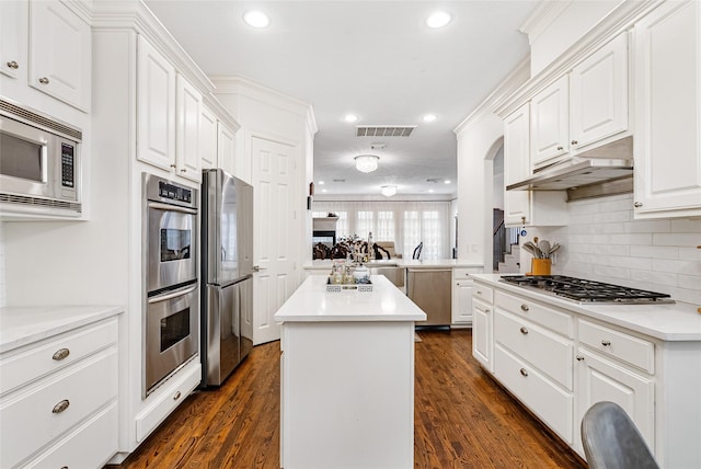 kitchen featuring white cabinetry, tasteful backsplash, a center island, appliances with stainless steel finishes, and dark hardwood / wood-style flooring