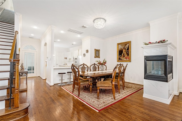 dining space with ornamental molding, dark hardwood / wood-style floors, and a multi sided fireplace